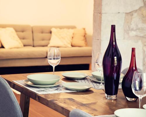 a wooden table with plates and wine glasses on it at THE RIVERSIDE LODGE Cozy and spacious apartment in Girona