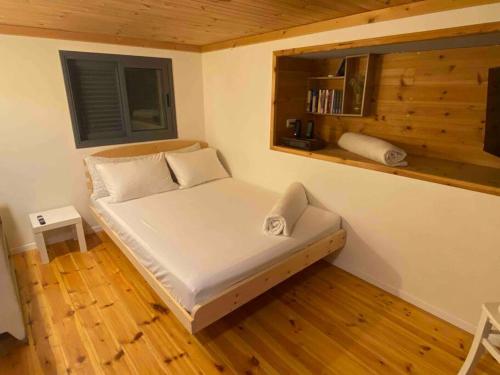 a small bed in a room with a wooden floor at Bit cabin near the airport in Kefar Daniyyel