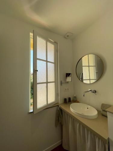 La salle de bains est pourvue d'un lavabo, d'un miroir et d'une fenêtre. dans l'établissement La villa des Amandiers, à Hyères