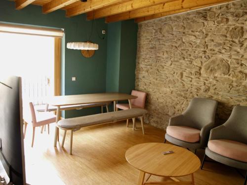 a dining room with a table and chairs and a stone wall at El Corral de Baró in Espot