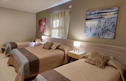 a room with three beds and a painting on the wall at Casas Noviembre in Plottier