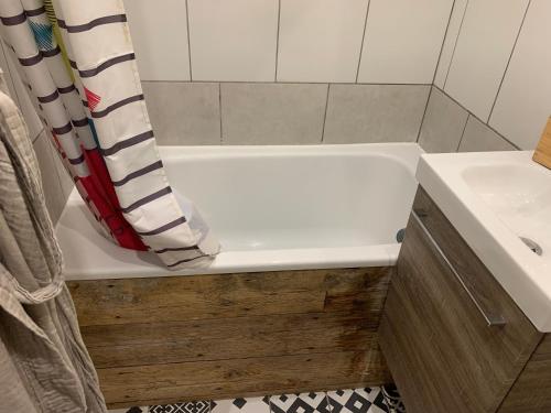La salle de bains est pourvue d'une baignoire blanche à côté d'un lavabo. dans l'établissement chambre avec salle de bain et cuisine privée centre ville historique avec climatisation et patio, à Bordeaux