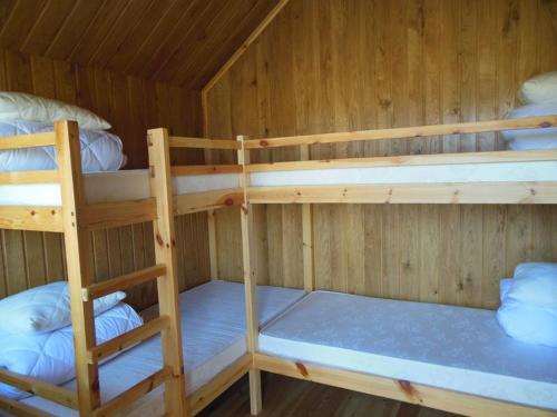 two bunk beds in a wooden cabin at Pūķarags - Kempings in Pape