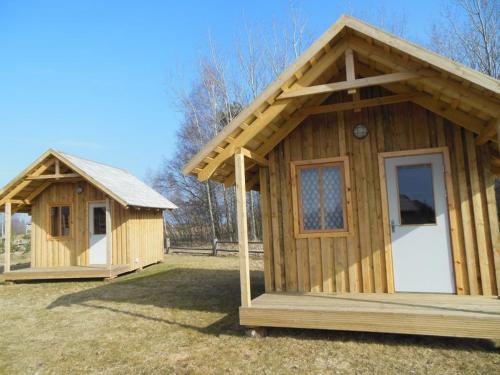 two small wooden buildings sitting on the grass at Pūķarags - Kempings in Pape
