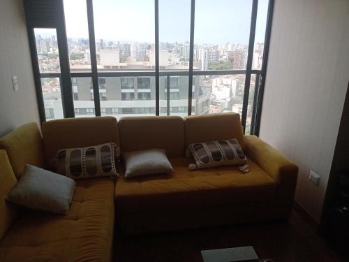 a couch in a room with a large window at Habitación nueva para persona sola o pareja in Lima