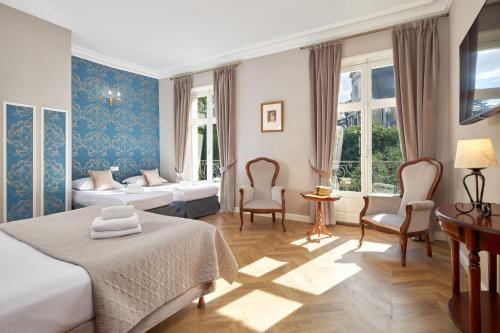 a hotel room with two beds and two chairs at H&ocirc;tel De France Et De Guise - 1891 in Blois