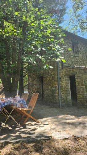 a table and chairs in front of a stone house at maisonnette avec jardin et terrasse in Montdardier