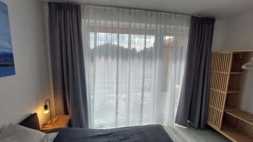 a bedroom with a large glass door with a window at Laguna24 Jezioro Żywieckie Klimatyzowany apartament 40 m2 in Zarzecze