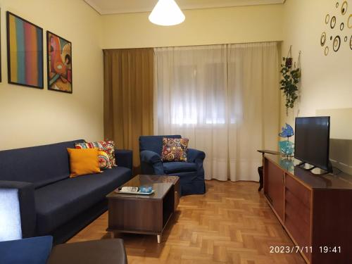 ein Wohnzimmer mit einem blauen Sofa und einem TV in der Unterkunft Anna's flat in Volos