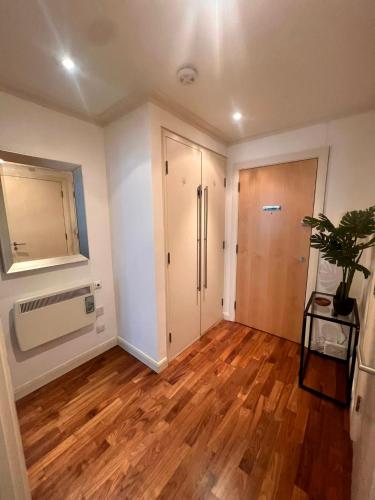 una sala de estar vacía con puerta y suelo de madera en NEW Spacious One Bed Apartment Near Canary Wharf, en Londres