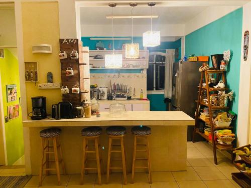 eine Küche mit einer Theke mit Hockern und einem Kühlschrank in der Unterkunft Residence Mish in Mahébourg