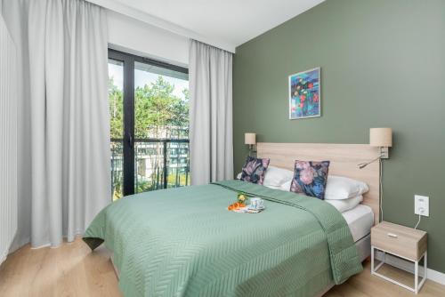 a bedroom with a green bed and a window at Shellter Suita Flora by Renters Prestige in Rogowo