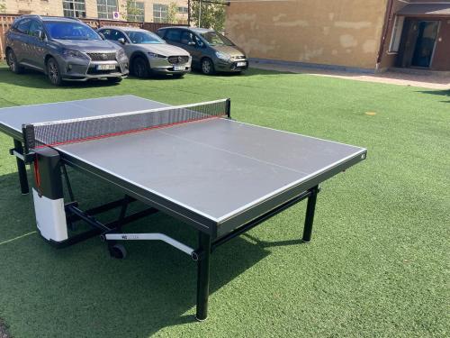 a ping pong table in a parking lot with parked cars at Viesu Nams Dzirkaļi in Ventspils