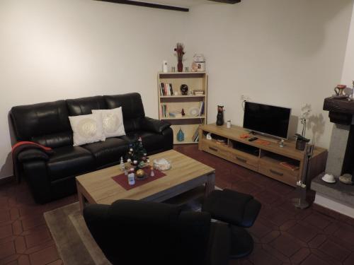 a living room with a black leather couch and a television at Armonia edificio storico del 1563. in Cevio