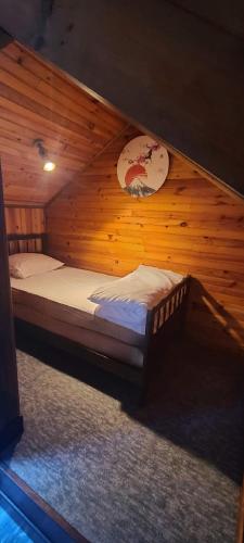 une chambre avec un lit dans une pièce en bois dans l'établissement Maisonnette Lac de Vassivière, à Beaumont