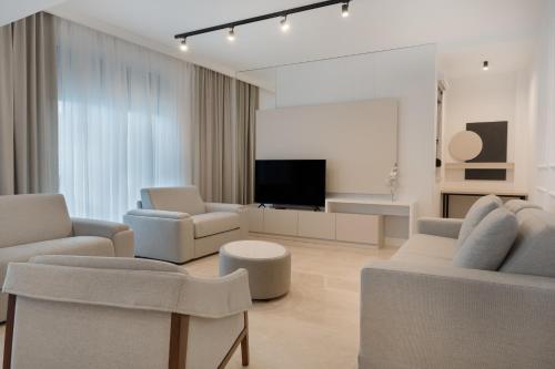 a living room with white furniture and a flat screen tv at Kondo Hotel Allure in Budva