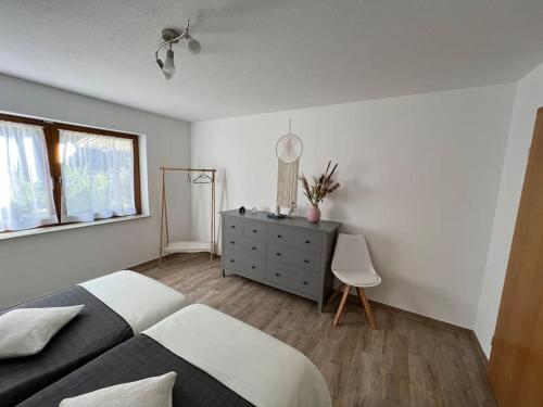 a bedroom with a bed and a dresser and a window at Bachgeflüster in Weilheim