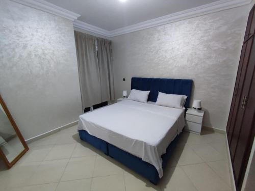 um quarto com uma cama grande e uma cabeceira azul em Centre Réception tanger près de la plage em Tânger