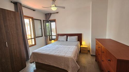 Schlafzimmer mit einem Bett, einer Kommode und einem Fenster in der Unterkunft Callao Sun & Pool in Callao Salvaje