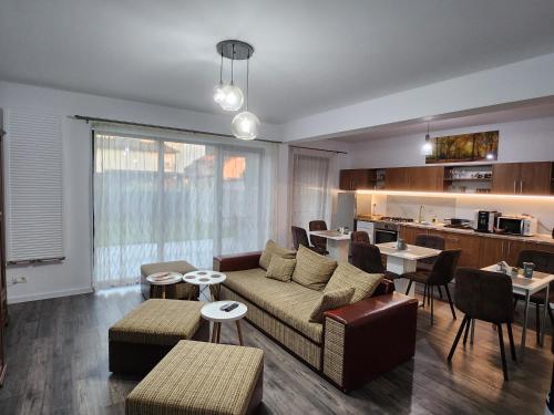 ein Wohnzimmer mit einem Sofa und Tischen sowie eine Küche in der Unterkunft Armina's Residence 2 in Dumbrăviţa
