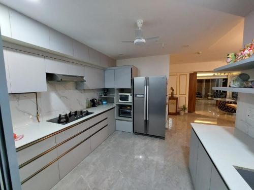La cuisine est équipée de placards blancs et d'un réfrigérateur en acier inoxydable. dans l'établissement Royal Nest Premium, à Pune