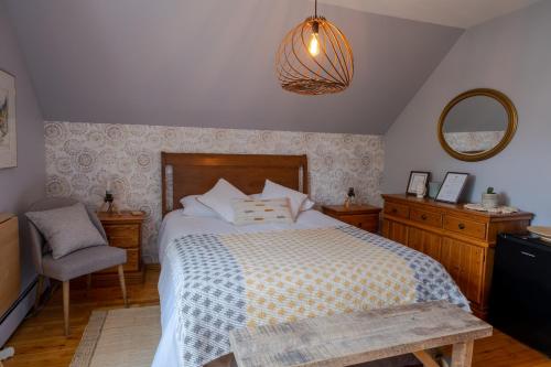 1 dormitorio con cama, silla y espejo en Au coq du bonheur en Magog-Orford