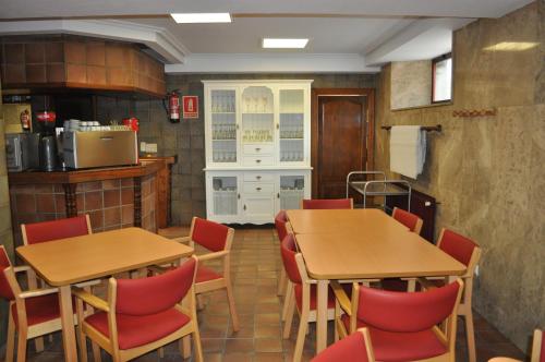 Hostal La Tablada في نافالينو: غرفة طعام مع طاولتين وكراسي حمراء