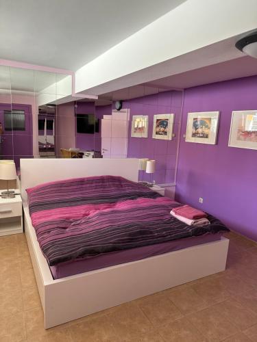 a bedroom with purple walls and a large bed at Casa Portocalie in Cisnădie