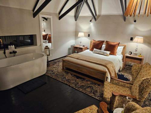 1 dormitorio con 1 cama grande y bañera en Tarry-Stone Cottages, en Dullstroom