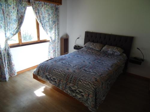 a bedroom with a bed and a window with curtains at Casa Perez in San Martín de los Andes