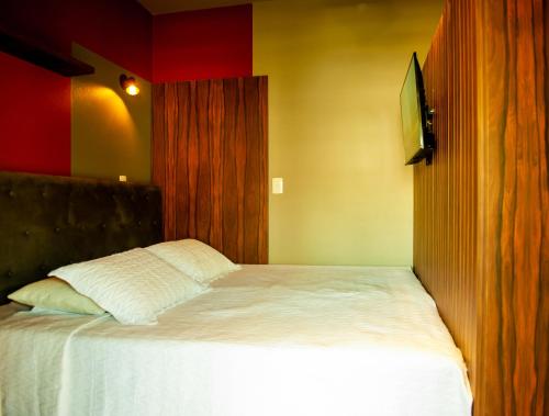 1 dormitorio con cama blanca y pared roja en HOSPEDAGEM CASA COMPACTA, en Jaraguá do Sul