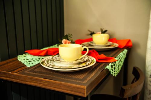 dos tazas y platillos en una mesa con servilletas rojas en HOSPEDAGEM CASA COMPACTA, en Jaraguá do Sul