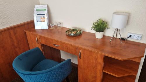 a wooden desk with a blue chair and a lamp at Sport Hotel in Tatabánya