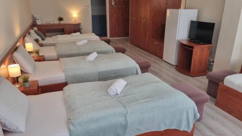 a hotel room with four beds and a television at Sport Hotel in Tatabánya