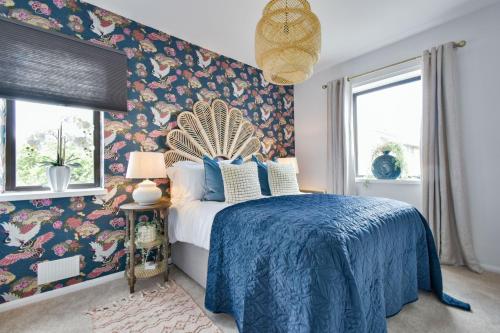 a bedroom with a blue bed with a floral wallpaper at Luxury Spacious 2 bed Apartment in Shilton