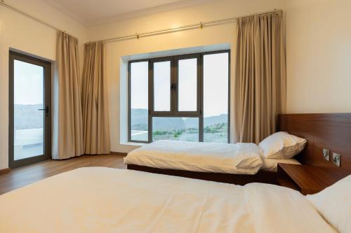 a hotel room with two beds and a large window at Horizon Villa in Qurayyah