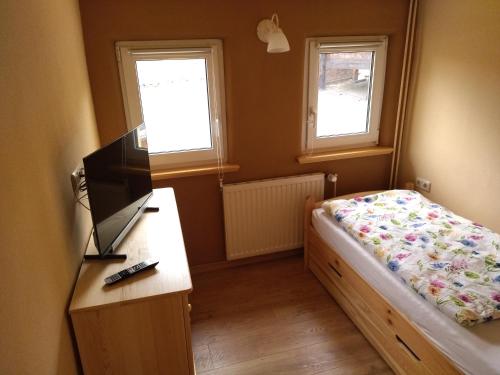 1 dormitorio con 1 cama y escritorio con TV en Schmal & Hoch - Willkommen im schmalsten Haus von Bad Frankenhausen, en Bad Frankenhausen