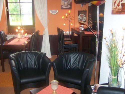 a dining room with black leather chairs and a table and a table and a table at Hotel Am Ufer in Trier