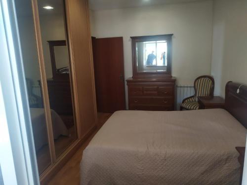 a bedroom with a bed and a dresser and a mirror at Bela moradia T3, solarenga e espaçosa 