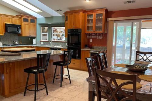 a kitchen with wooden cabinets and a table with bar stools at Mountain Haven: Wi-Fi, Luxe Views, Hot Tub close to Bass Lake, Yosemite in Oakhurst