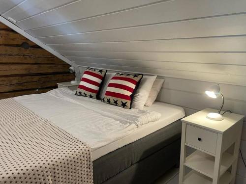 uma cama com almofadas vermelhas e brancas num quarto em Suloinen luhtirakennus Randla em Rauma