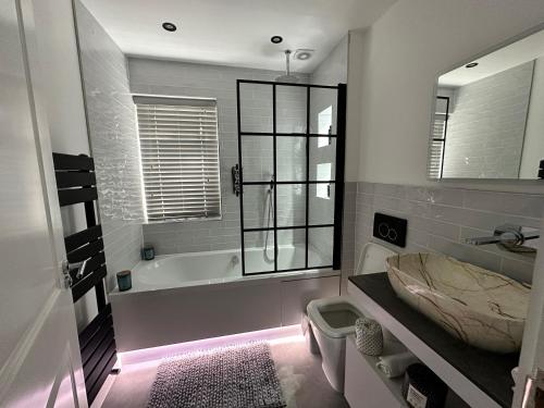 a bathroom with a bath tub and a sink at A luxury brand-new apartment in Barnet