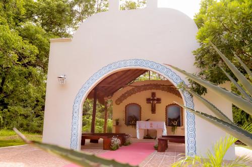 an archway leading to a church with a cross at Mayan Secret Hotel Boutique in Chetumal