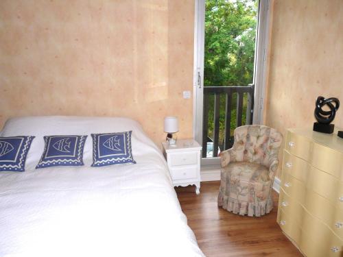 a bedroom with a bed and a chair and a window at le cottage vue mer in Bénerville-sur-Mer