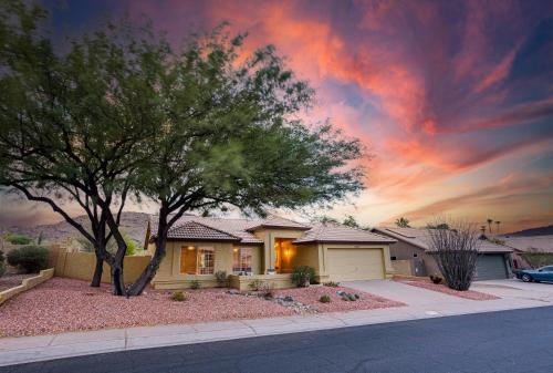 a house with a tree in front of a sunset at Western Star Ahwatukee home in Phoenix