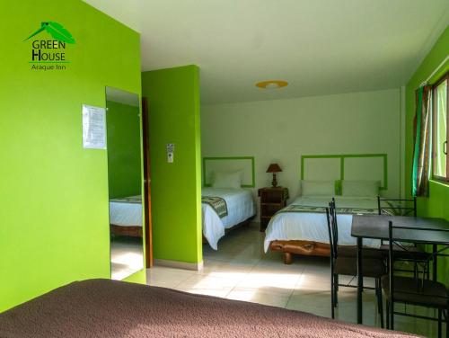 a green house bedroom with two beds and a table at Green House Araque Inn in Otavalo