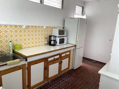 a kitchen with a white refrigerator and a microwave at La Villa Ti-Louise à Marie-Galante in Grand-Bourg