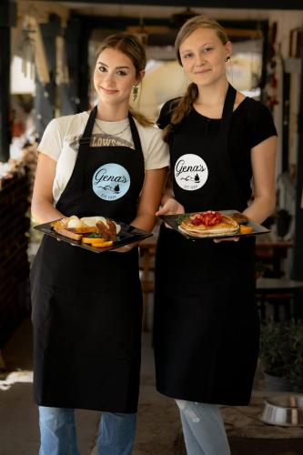 two women in black aprons holding plates of food at Genas's Sierra Inn & Restaurant in Dunlap