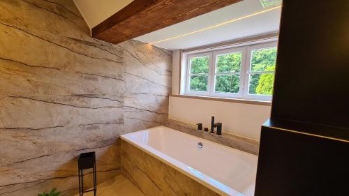 a bathroom with a bath tub and a window at Dom nad jeziorem in Lubniewice
