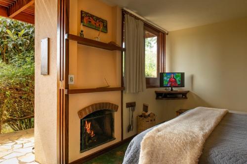 a bedroom with a fireplace and a bed and a television at Pousada Bicho do Mato in Gonçalves